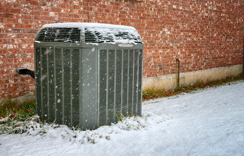 Een moderne warmtepomp staat in de sneeuw.